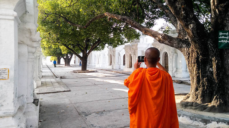 Monk taking a photo at Kuthodaw Pagoda in Mandalay, Myanmar